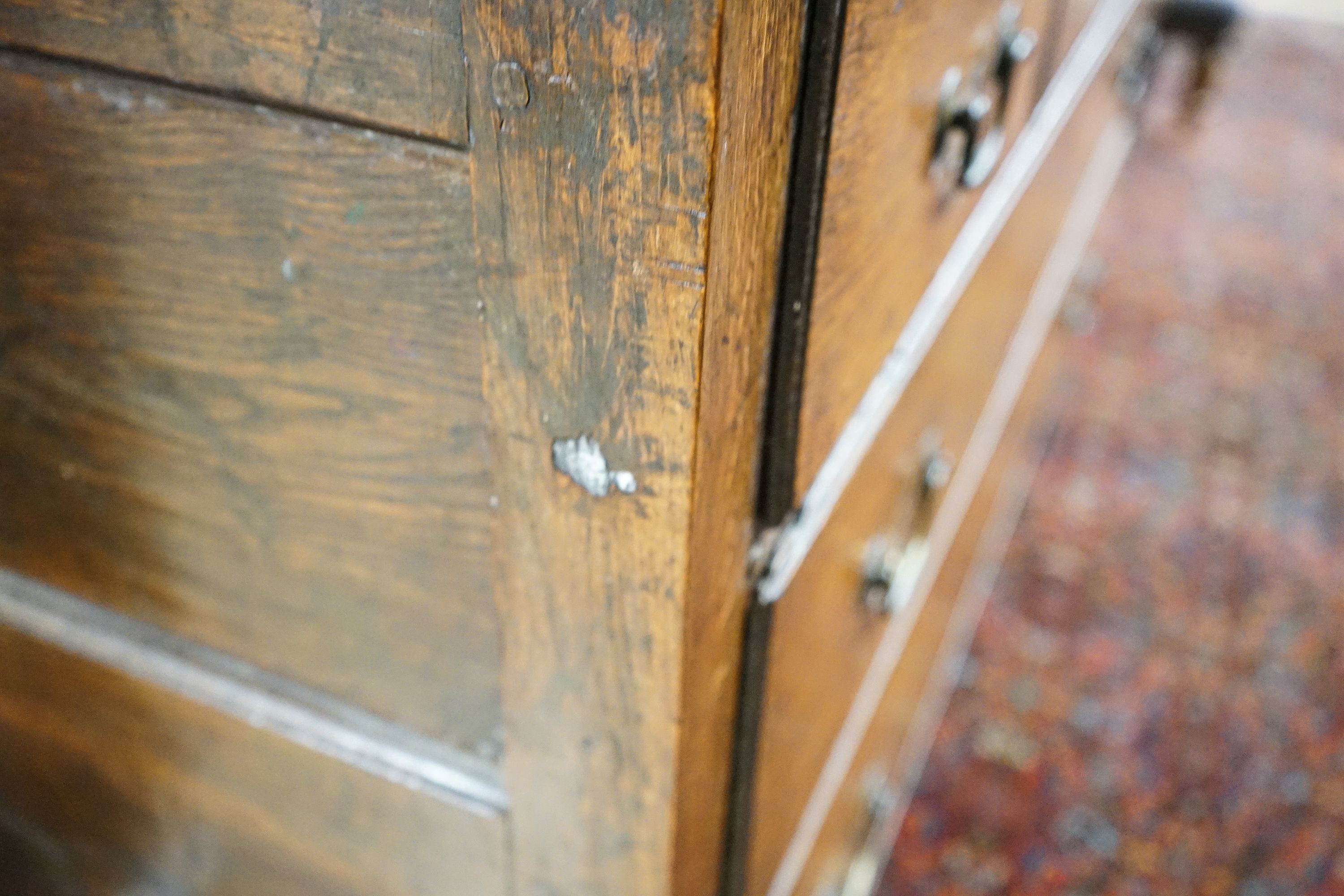 A George III oak press cupboard, with moulded cornice and two panelled doors over five drawers, width 122cm, depth 52cm, height 183cm